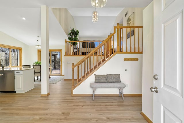 entryway featuring light wood-style flooring, stairs, and vaulted ceiling