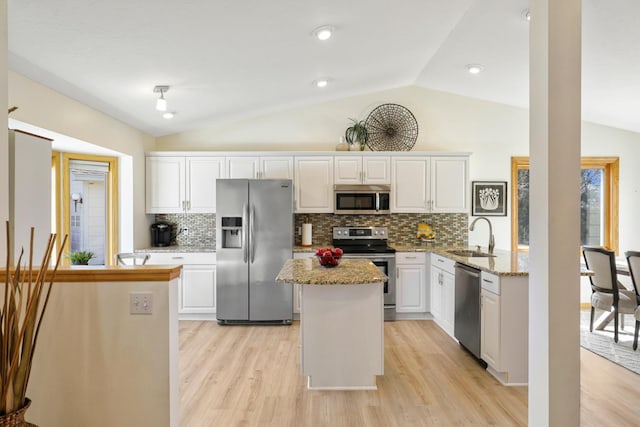 kitchen with white cabinetry, lofted ceiling, appliances with stainless steel finishes, and a sink