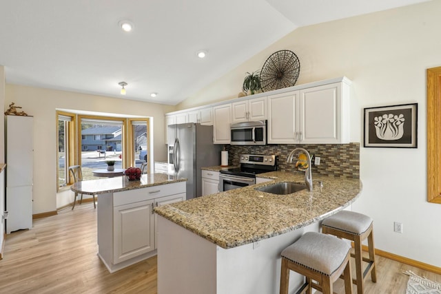 kitchen featuring tasteful backsplash, a center island, a peninsula, stainless steel appliances, and a sink