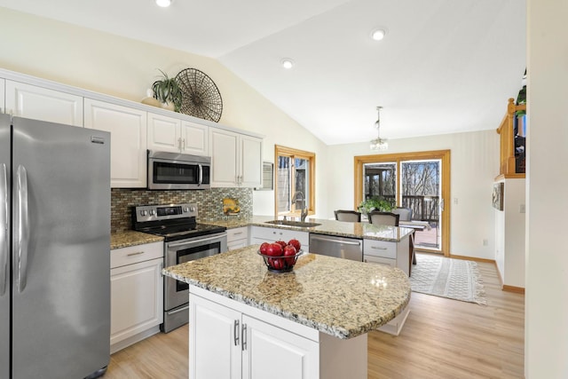 kitchen with a peninsula, lofted ceiling, a sink, stainless steel appliances, and a center island