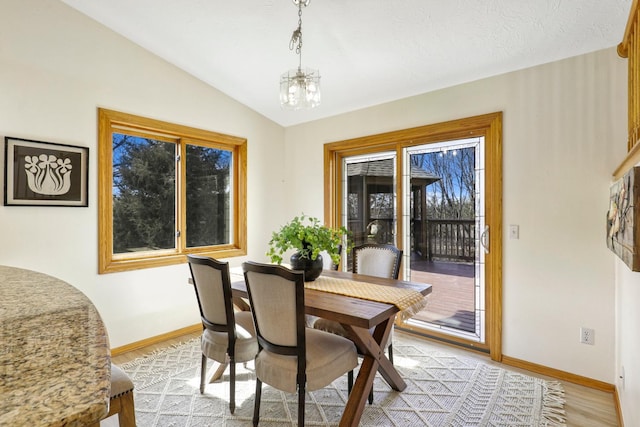 dining space featuring vaulted ceiling, baseboards, light wood-type flooring, and a chandelier