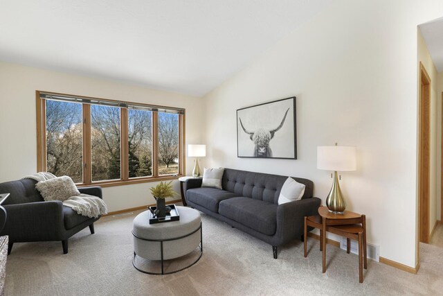 living area featuring visible vents, baseboards, light colored carpet, and vaulted ceiling