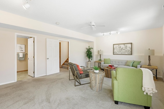 carpeted living area with stairway, baseboards, track lighting, and a ceiling fan