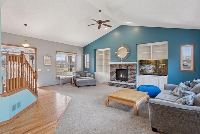 living area featuring built in features, a ceiling fan, visible vents, vaulted ceiling, and a brick fireplace