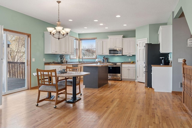 kitchen featuring a sink, a center island, stainless steel appliances, an inviting chandelier, and white cabinets