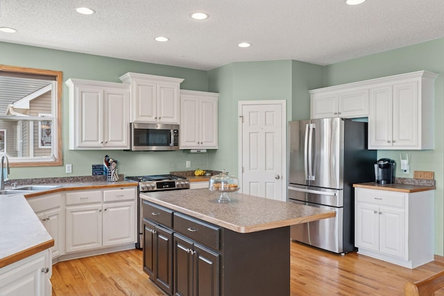 kitchen featuring a sink, stainless steel appliances, light wood-style floors, and white cabinets