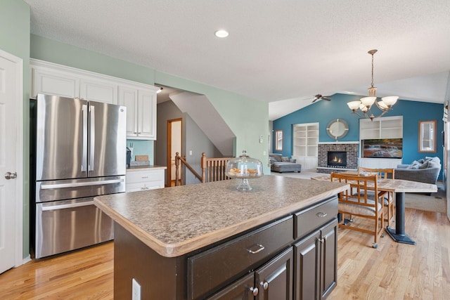 kitchen featuring light wood finished floors, a center island, lofted ceiling, freestanding refrigerator, and white cabinetry