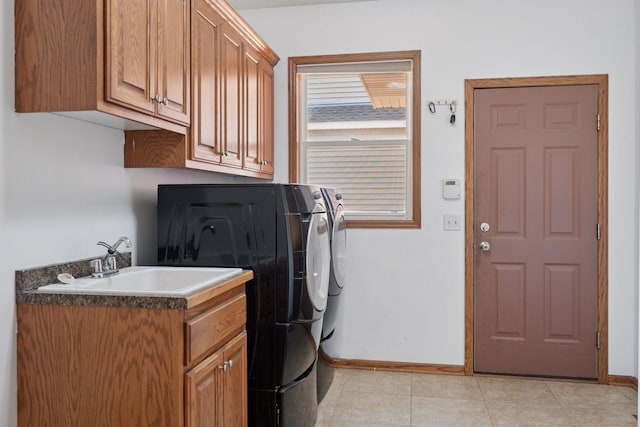 laundry area with baseboards, light tile patterned flooring, cabinet space, a sink, and independent washer and dryer