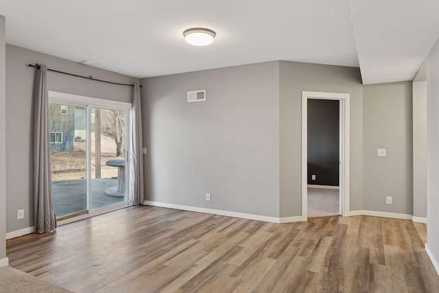 spare room with visible vents, baseboards, and wood finished floors