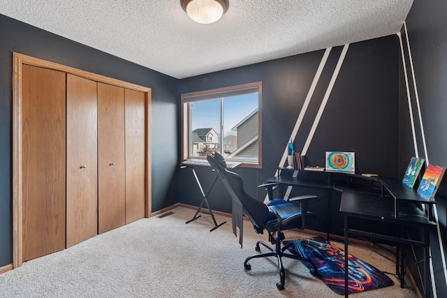 carpeted home office with a textured ceiling and baseboards