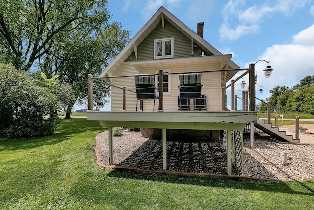 back of house featuring a chimney, a wooden deck, and a yard