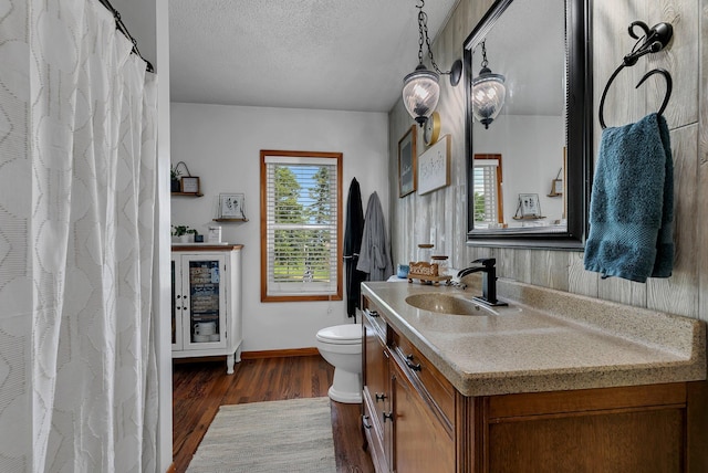 bathroom featuring vanity, wood finished floors, baseboards, a textured ceiling, and toilet