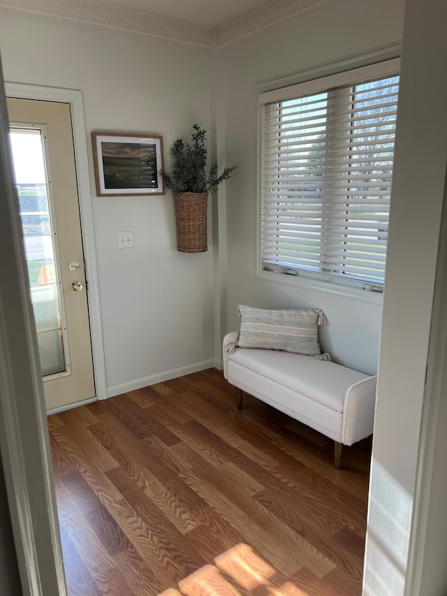 living area with wood finished floors, crown molding, and baseboards