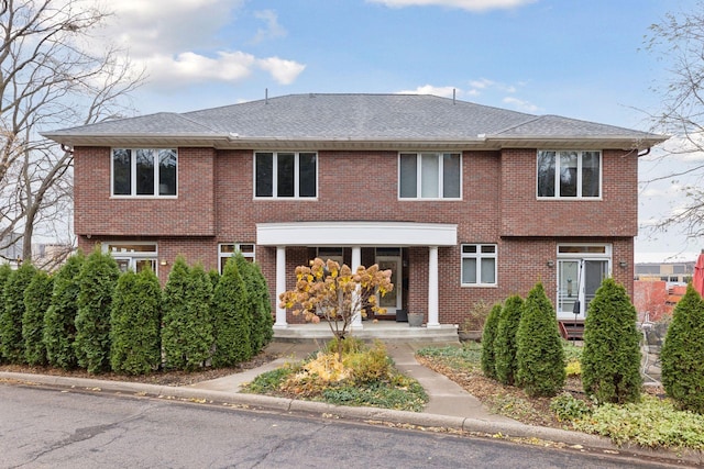 view of front facade with brick siding and roof with shingles