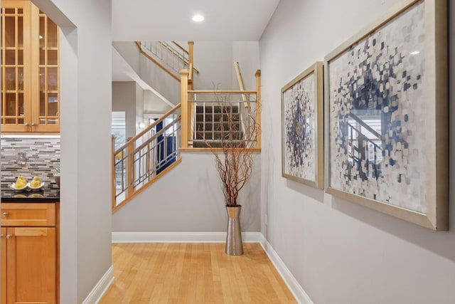 hall featuring recessed lighting, light wood-type flooring, baseboards, and stairs