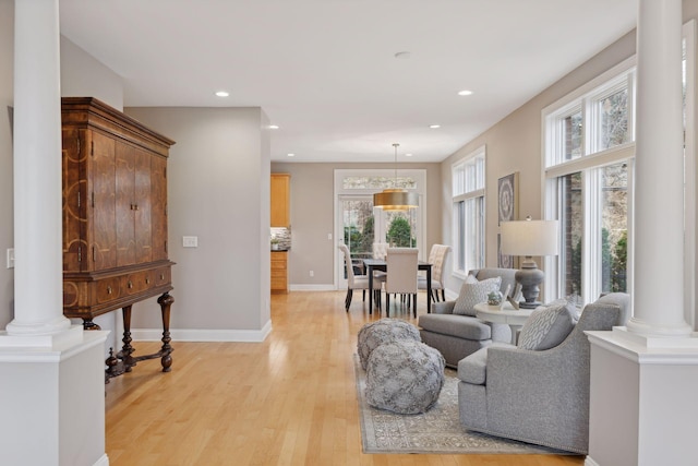 living area with light wood finished floors, recessed lighting, baseboards, and ornate columns