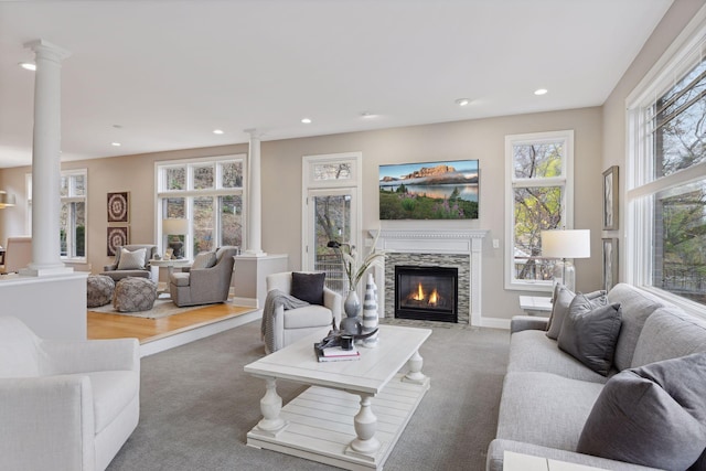 living room with light carpet, a glass covered fireplace, recessed lighting, and ornate columns