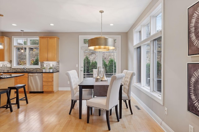 dining space featuring visible vents, light wood-style floors, baseboards, and a wealth of natural light