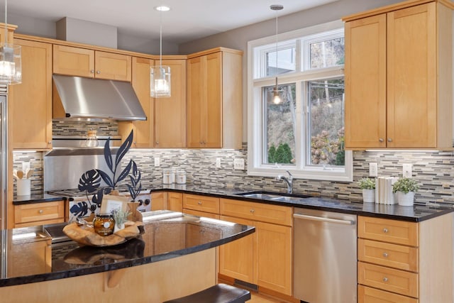 kitchen featuring under cabinet range hood, light brown cabinetry, dark stone countertops, stainless steel dishwasher, and a sink