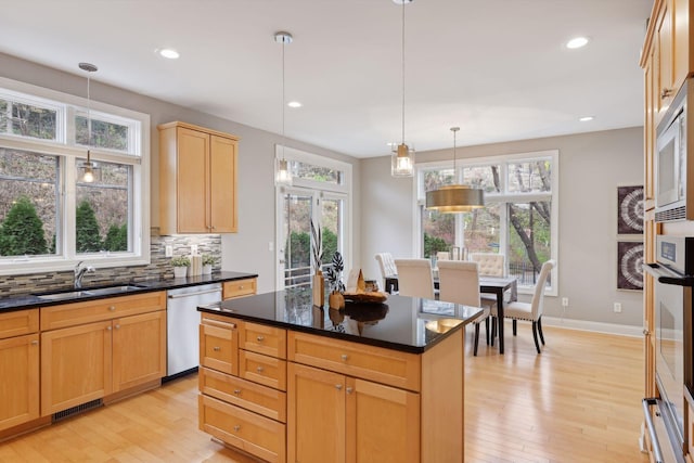 kitchen featuring visible vents, a sink, light wood-style floors, dishwasher, and backsplash