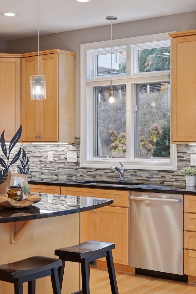 kitchen featuring backsplash, stainless steel dishwasher, and light brown cabinetry