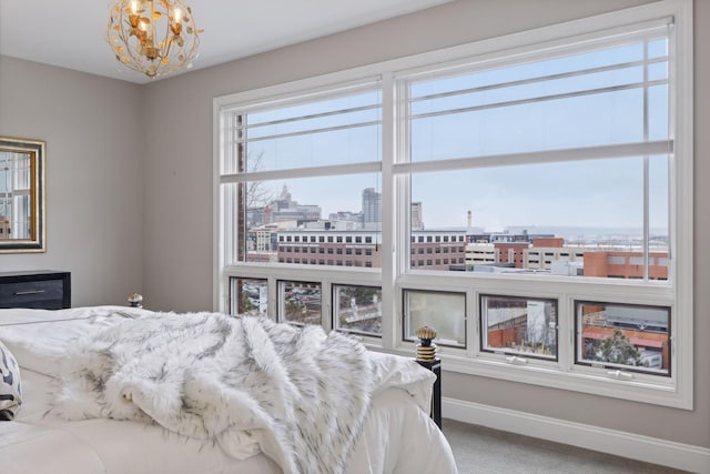 carpeted bedroom featuring a city view, an inviting chandelier, and baseboards