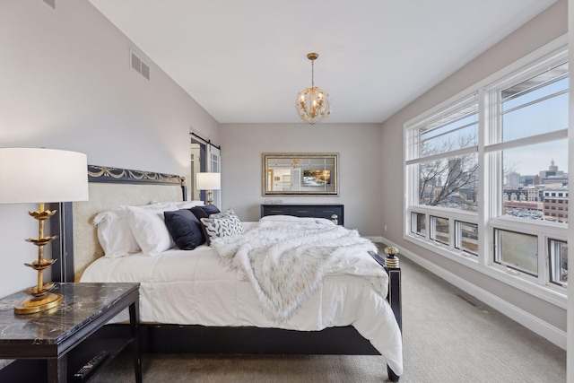 bedroom featuring visible vents, a notable chandelier, a barn door, carpet flooring, and baseboards