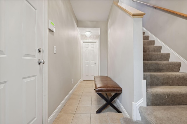 interior space featuring stairs, light tile patterned floors, and baseboards