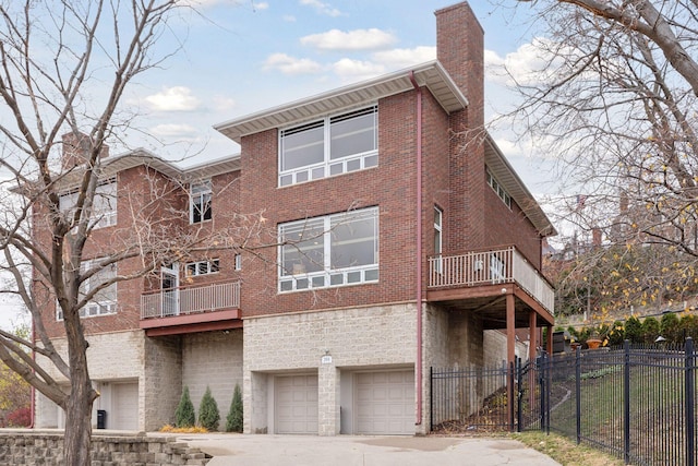 back of property with brick siding, fence, a chimney, driveway, and an attached garage