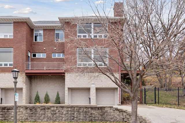 view of property featuring an attached garage, fence, and driveway