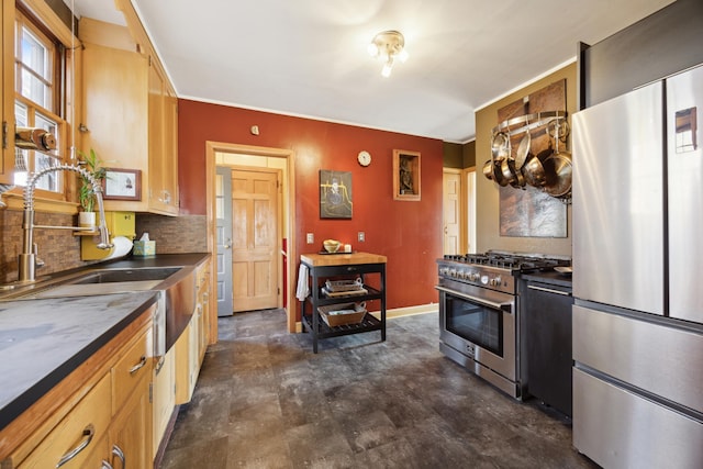 kitchen featuring baseboards, a sink, decorative backsplash, appliances with stainless steel finishes, and dark countertops