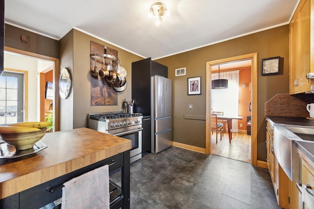 kitchen featuring visible vents, baseboards, wooden counters, stainless steel appliances, and crown molding