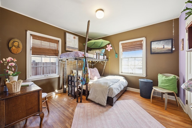 bedroom featuring baseboards, multiple windows, and wood finished floors