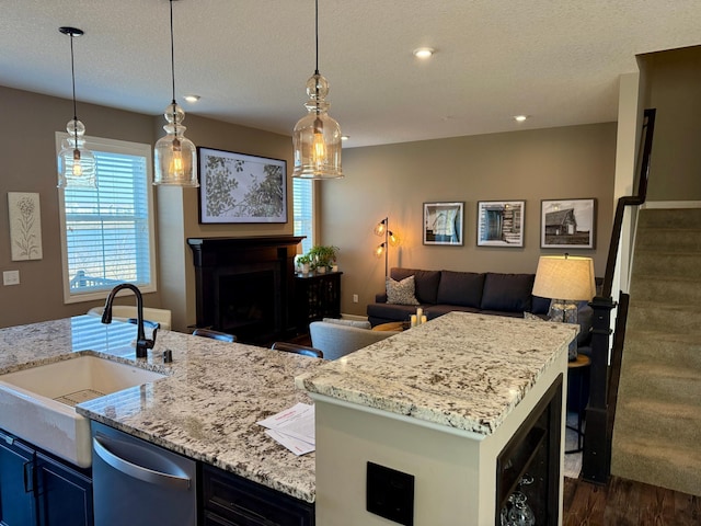 kitchen featuring a kitchen island, open floor plan, light stone counters, a fireplace, and a sink