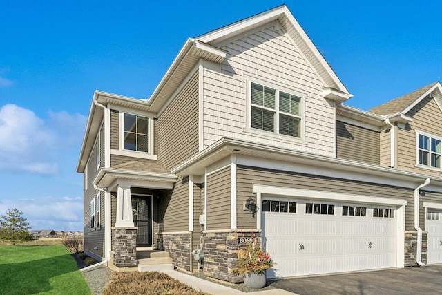 view of front of house featuring aphalt driveway, stone siding, and a garage