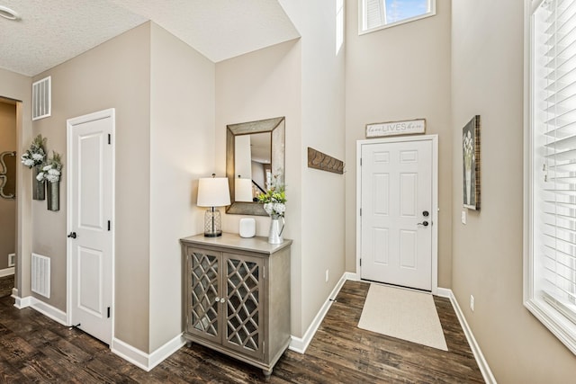 foyer with dark wood finished floors, baseboards, and visible vents