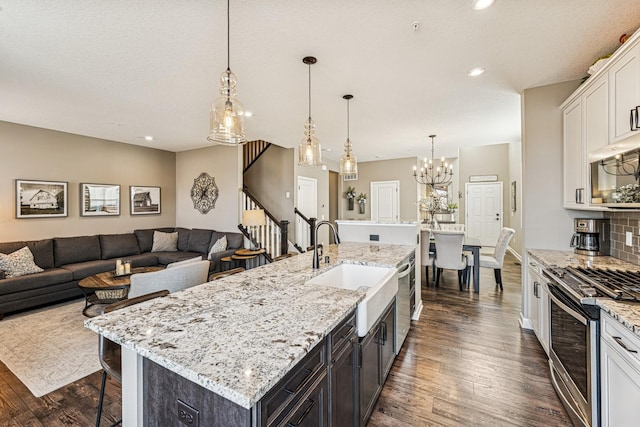 kitchen with a breakfast bar, appliances with stainless steel finishes, dark wood-style floors, white cabinets, and a sink