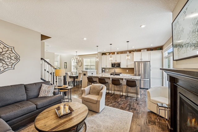 living room with a glass covered fireplace, stairs, dark wood finished floors, and a textured ceiling