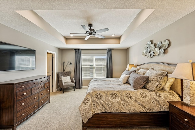 bedroom with light carpet, a tray ceiling, a textured ceiling, baseboards, and ceiling fan