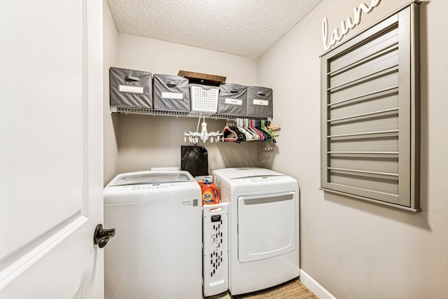 laundry area featuring washer and dryer, laundry area, baseboards, and a textured ceiling