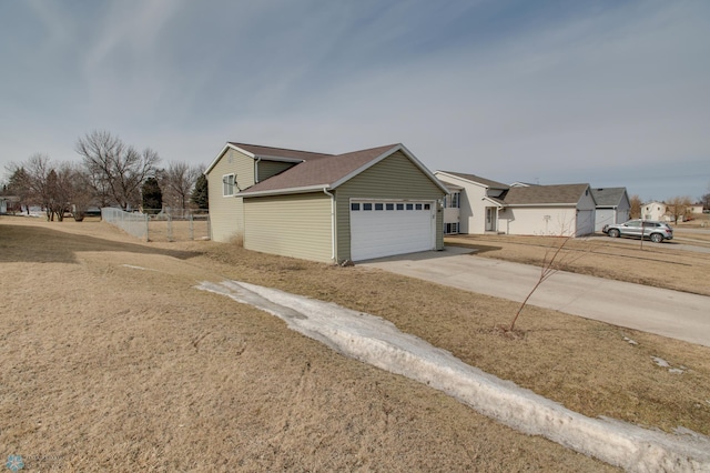 view of property exterior featuring concrete driveway, fence, and a garage