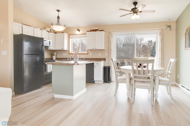 kitchen featuring stainless steel microwave, a kitchen island, white cabinetry, freestanding refrigerator, and light wood finished floors