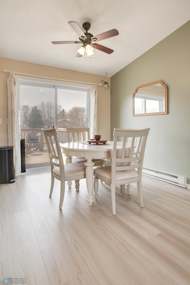 dining space with ceiling fan, baseboard heating, wood finished floors, and a textured ceiling