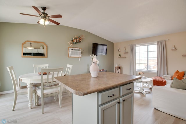 kitchen with light wood-type flooring, a kitchen island, light countertops, ceiling fan, and vaulted ceiling