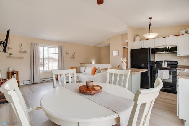 dining area with baseboard heating, light wood-style flooring, and lofted ceiling