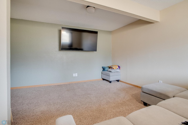 carpeted living area with beam ceiling and baseboards