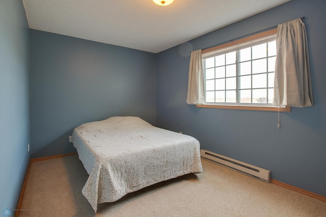 carpeted bedroom featuring a baseboard heating unit and baseboards