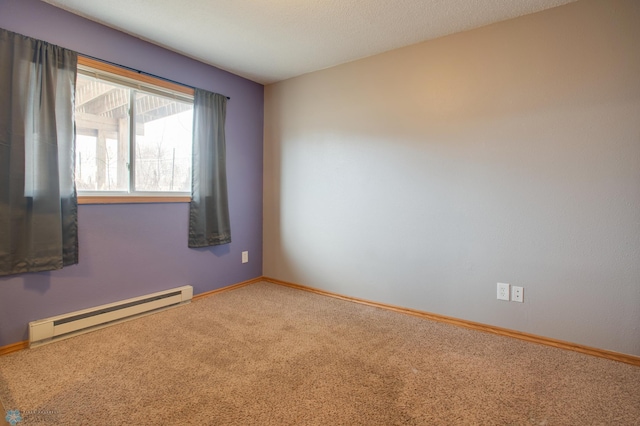 spare room featuring a baseboard heating unit, carpet, and baseboards