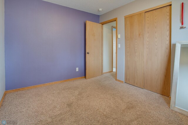 unfurnished bedroom featuring baseboards, carpet, a closet, and a textured ceiling