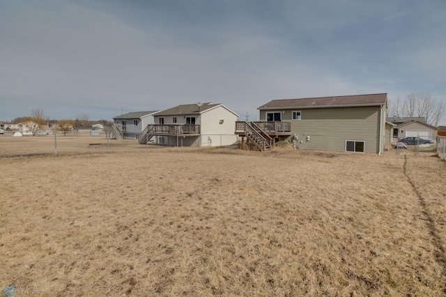 rear view of house featuring a wooden deck, stairway, and fence